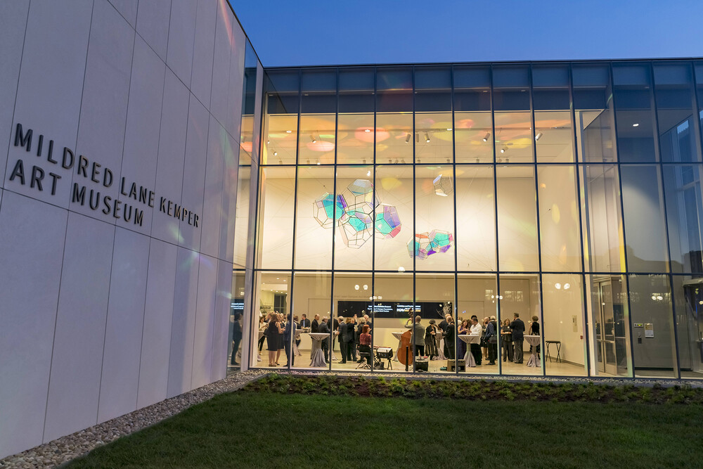 Exterior view of the Mildred Lane Kemper Art Museum at night with people visible through the windows