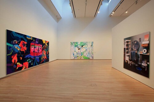 A view of a gallery with three walls in view. There is a large, multi-colored canvas on each wall.